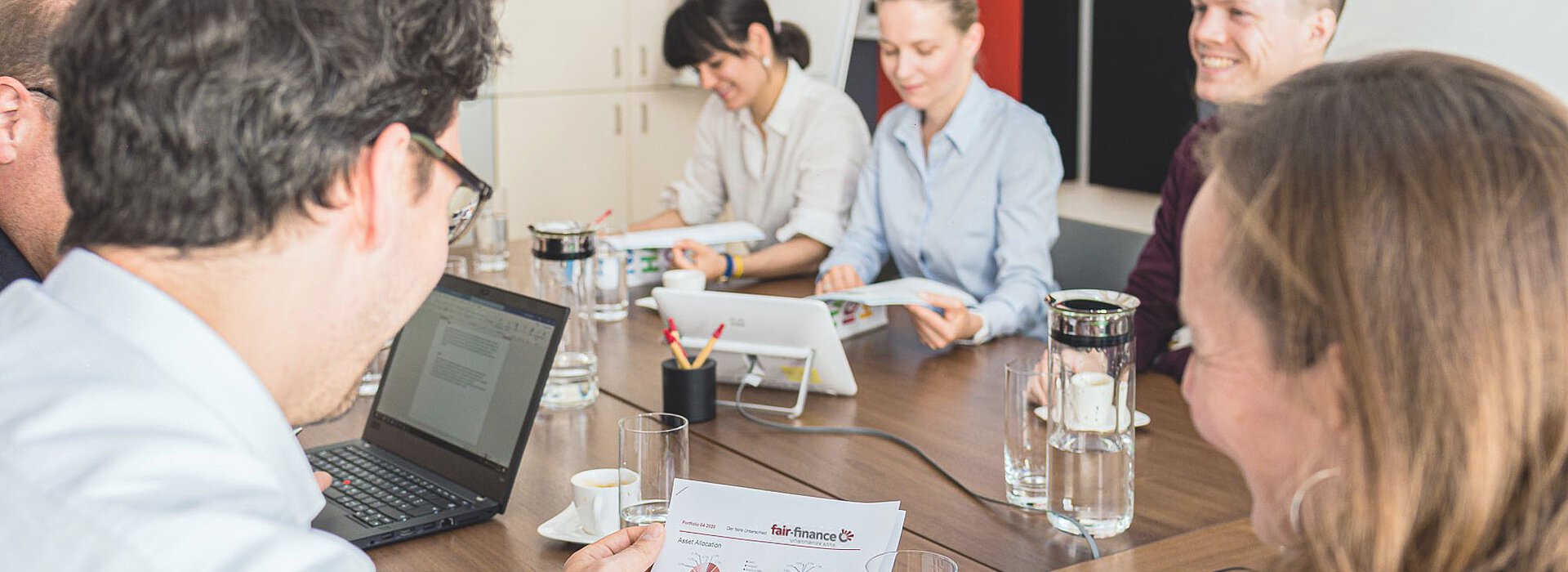 Gruppenfoto fair-finance MitarbeiterInnen Gruppenfoto: fair-finance MitarbeiterInnen sitzen gemeinsam am Besprechungstisch