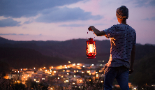 Junge blickt über die Stadt Ein Junge hält eine Lampe in der Hand und blickt über die beleuchtete Stadt